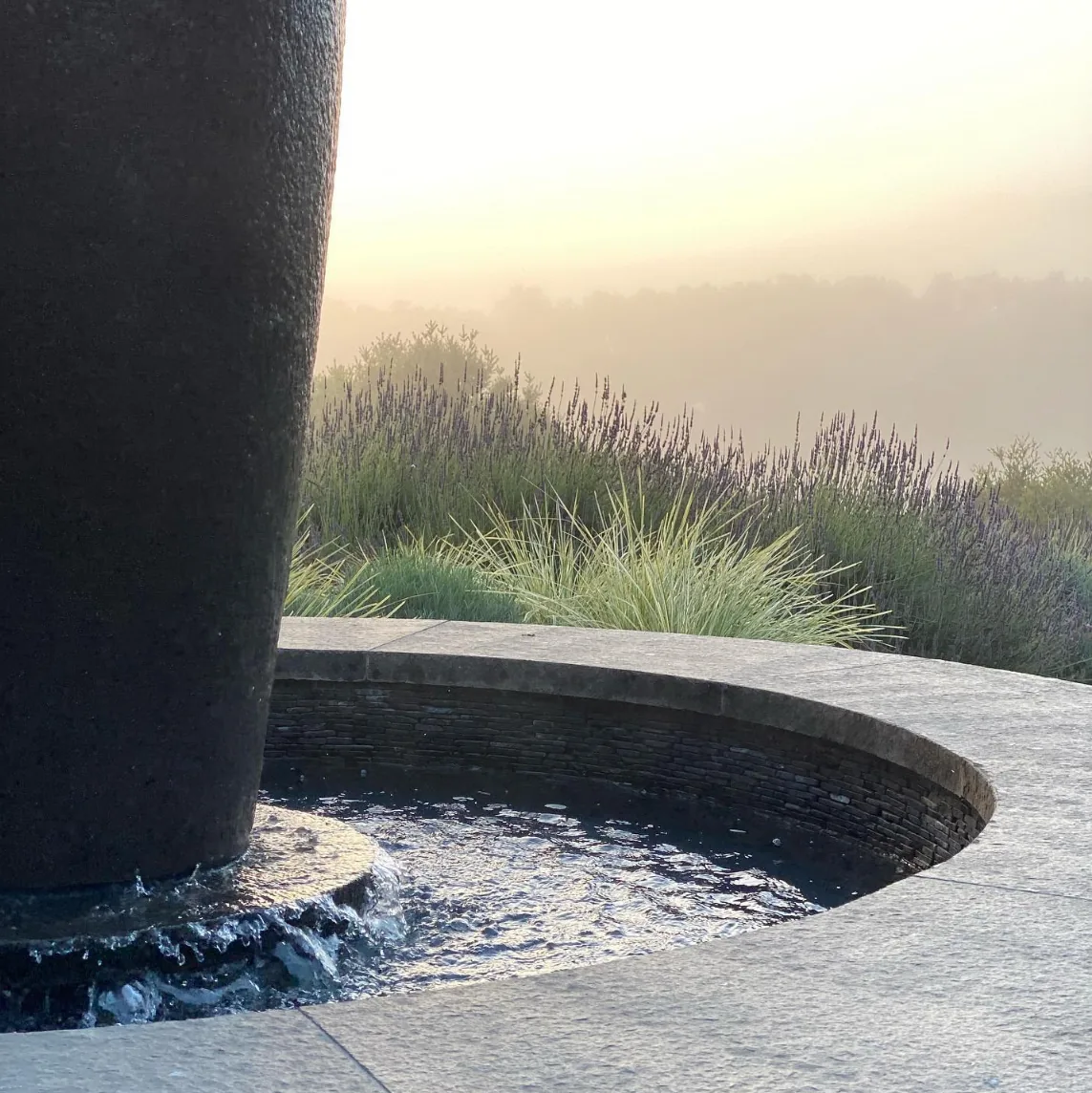 Carmel Contemporary Hacienda — the dark fountain vessel and its stone basin against the evening sky