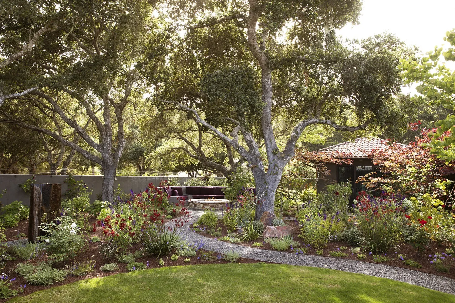Carmel Contemporary Hacienda — the sunken patio in the oak grove, a stone fire pit at its center, the house beyond