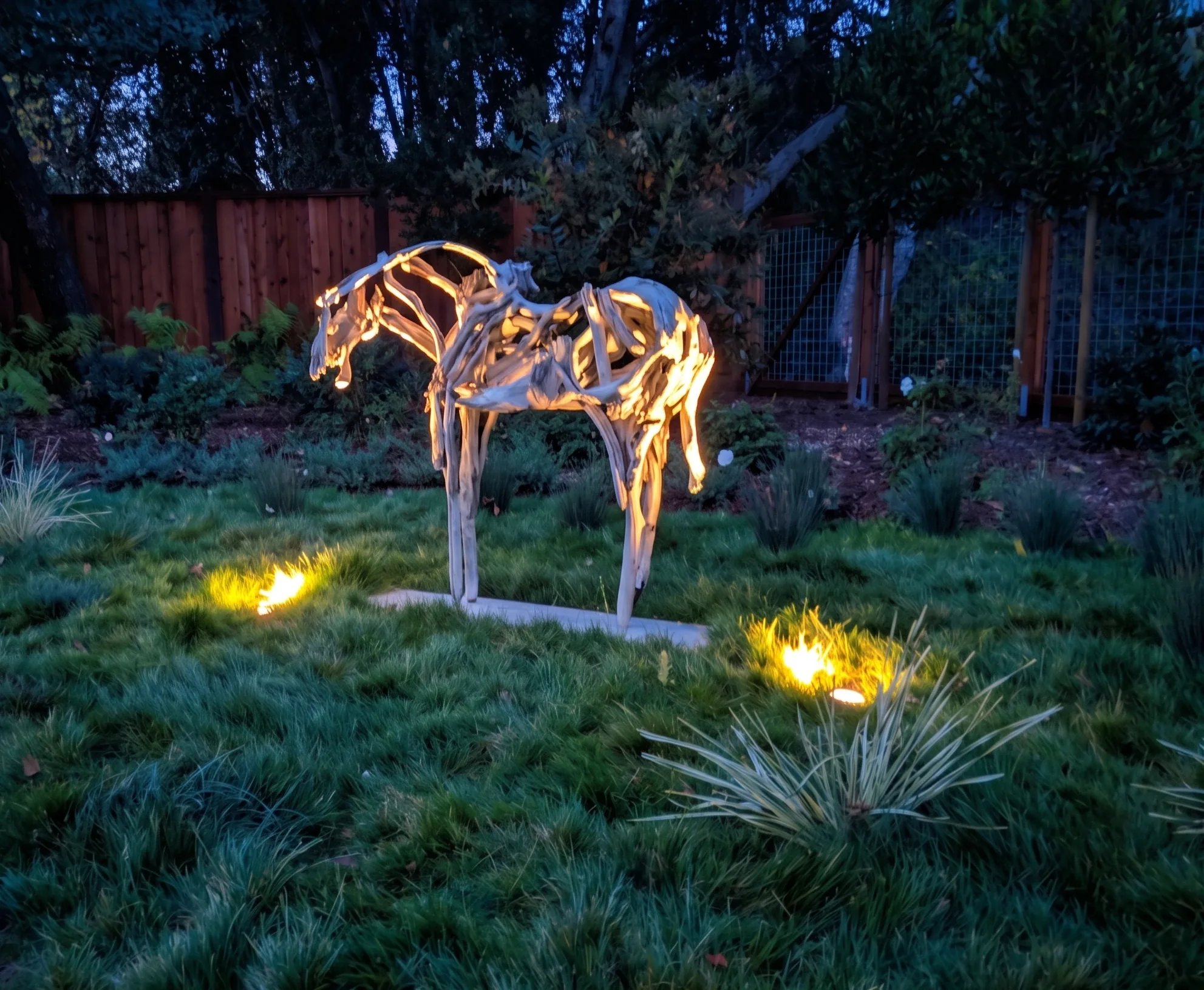 Lafayette Residence — a lit driftwood horse sculpture on the native bentgrass lawn at dusk, with garden uplighting