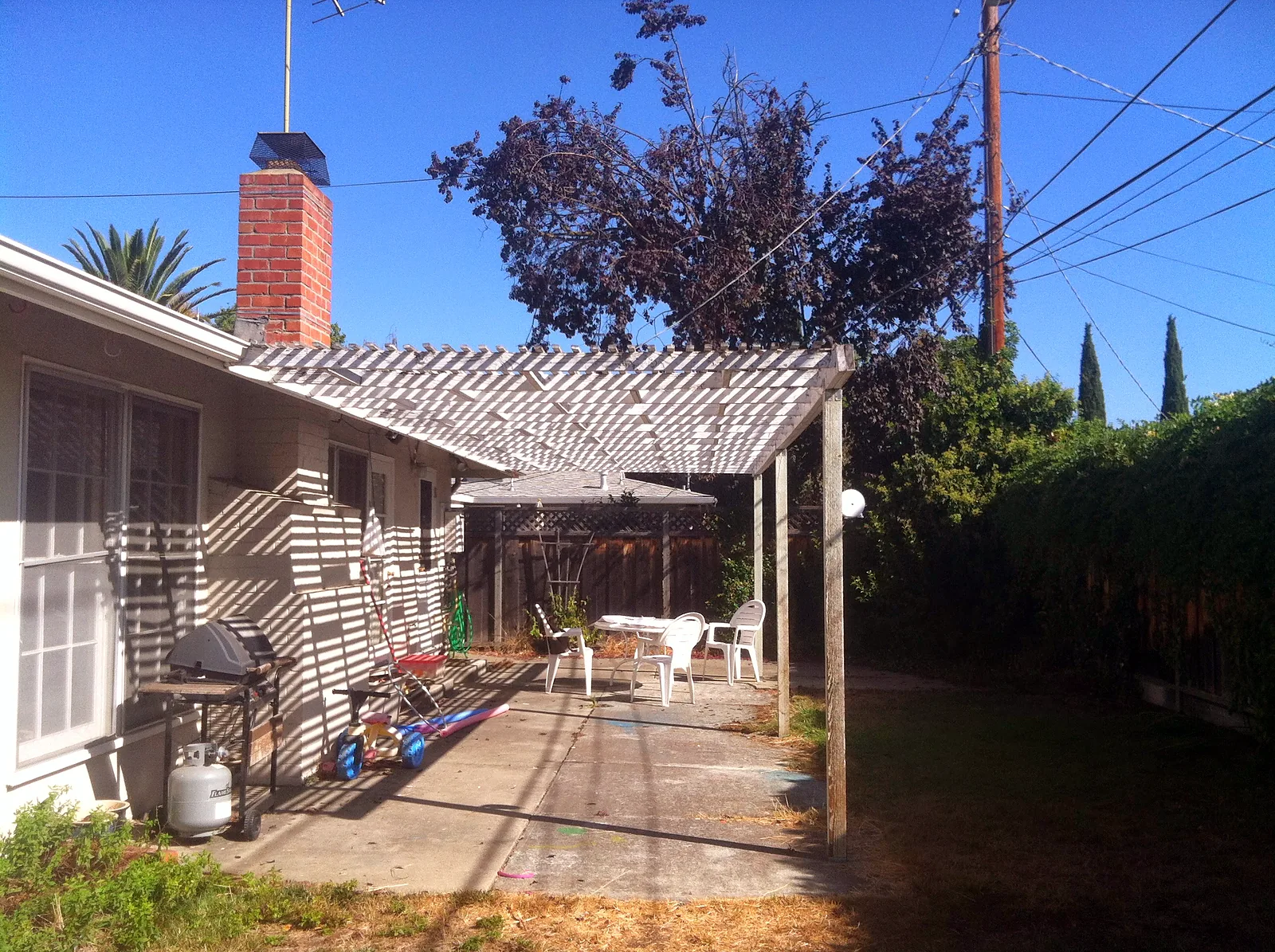 Before — the cracked concrete slab and sagging painted lattice cover over the old patio