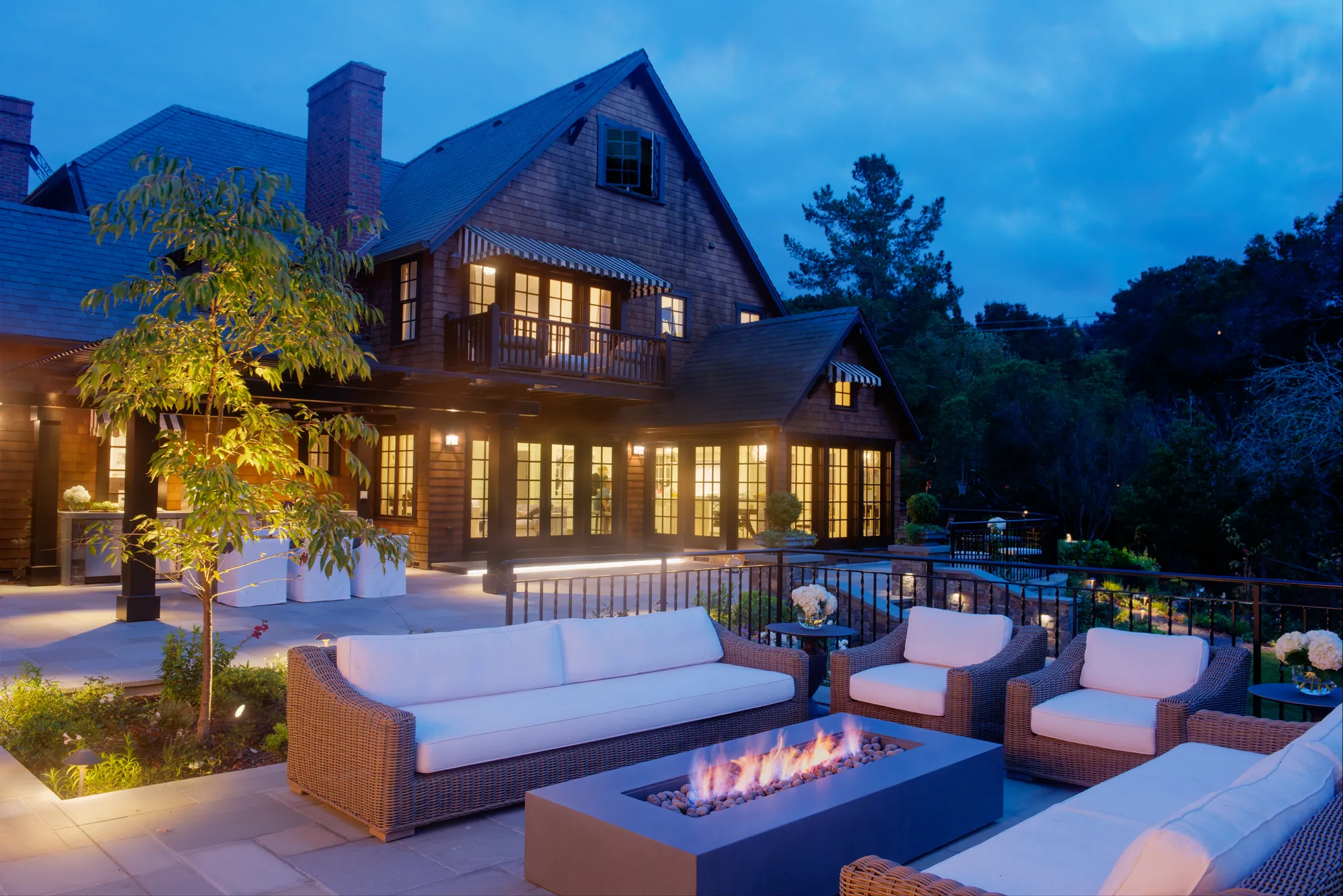 Orinda hillside residence — terrace and fire-pit lounge glowing at blue hour, with the house lit behind