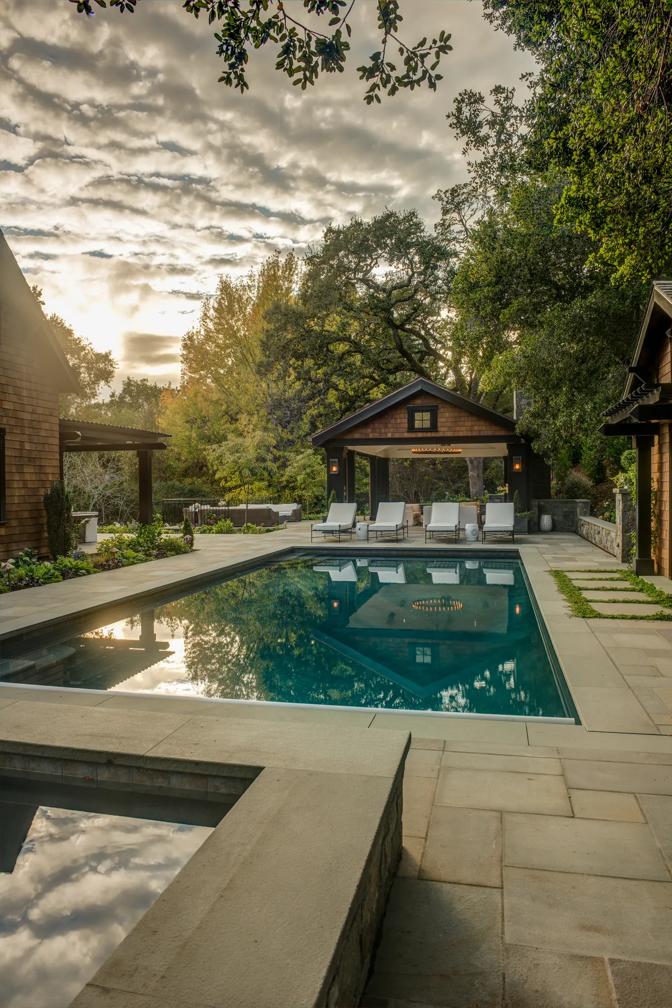 Orinda hillside residence — golden-hour pool and pavilion beneath a backlit oak