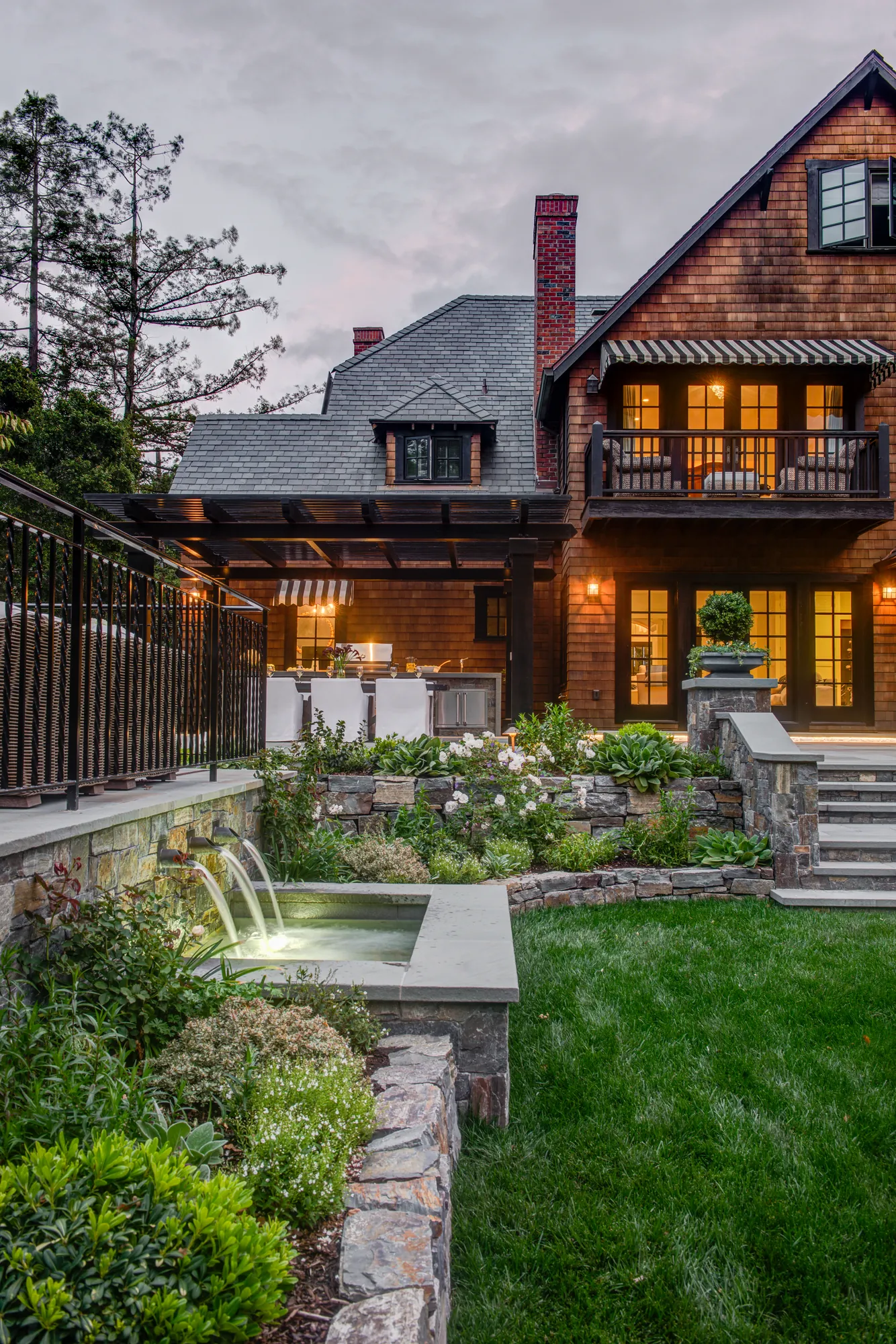 Orinda hillside residence — twilight terrace with glowing fountain and lit house