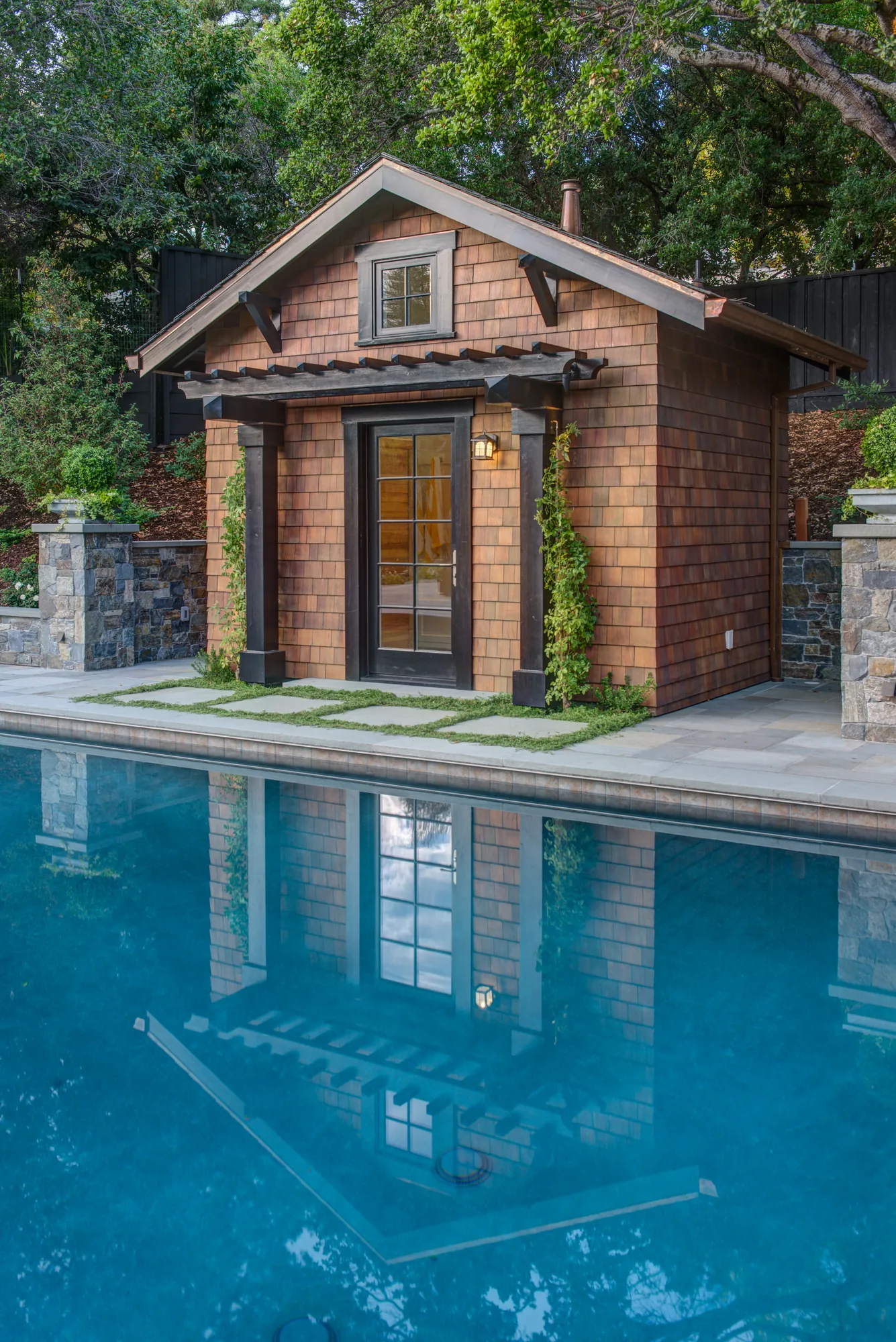 Orinda hillside residence — shingled poolhouse mirrored in the still pool
