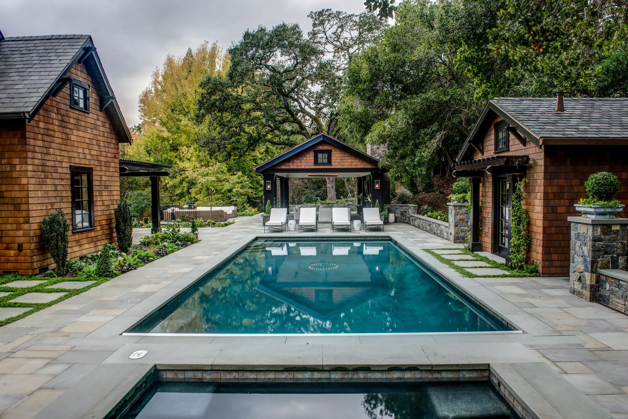 After — the rebuilt pool in cut stone with planted joints, the open-air pavilion set at its head and a spa in the foreground