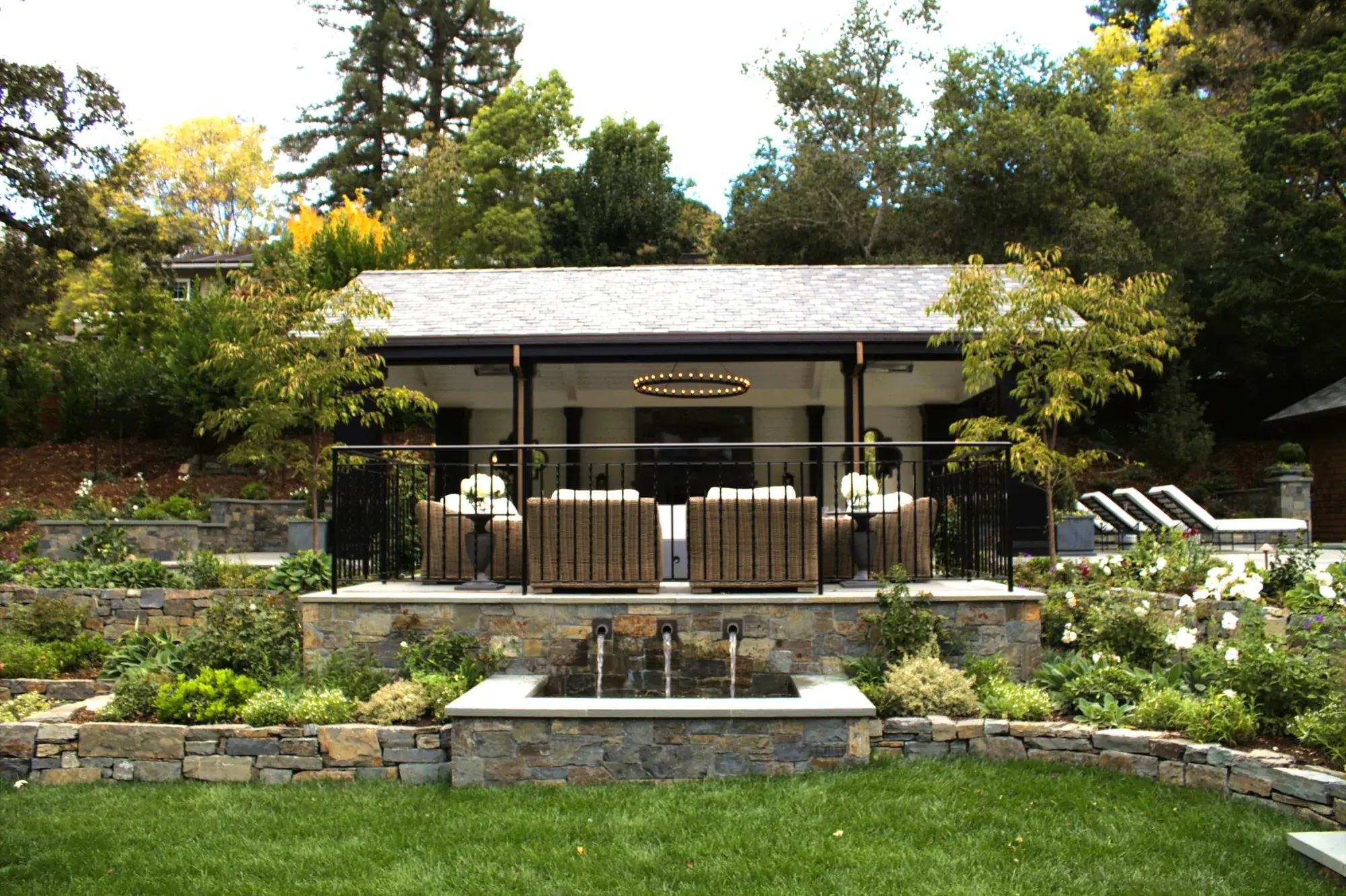 After — a stone wall spouting into a rectangular basin, with terraced planting and the pavilion terrace above