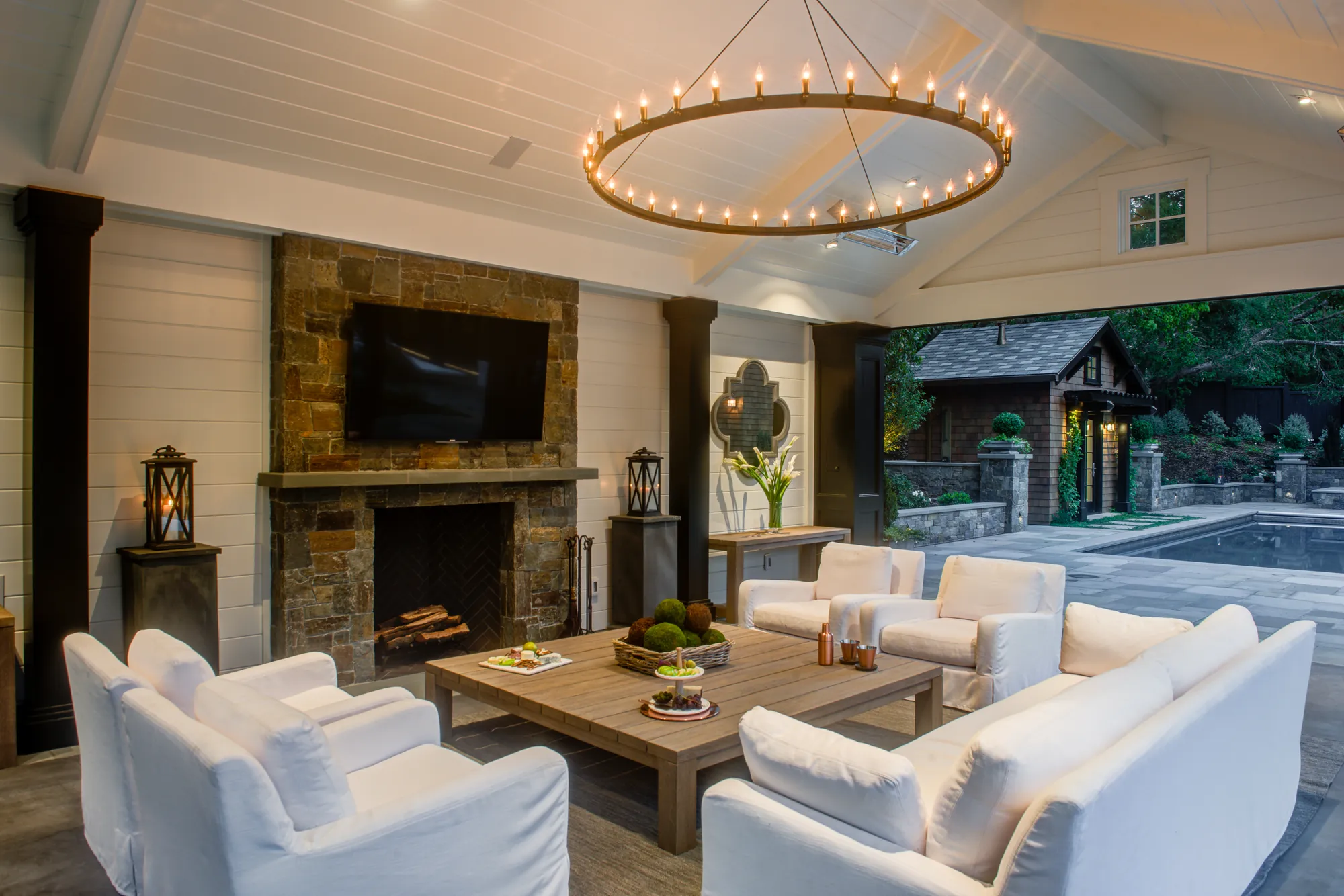 Orinda hillside residence — inside the pavilion, the stone fireplace and seating with the pool beyond