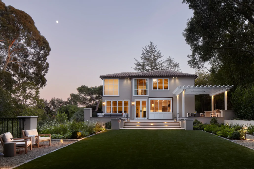 Piedmont Residence at dusk — the lit villa seen across the level lawn, with a moon above the trees